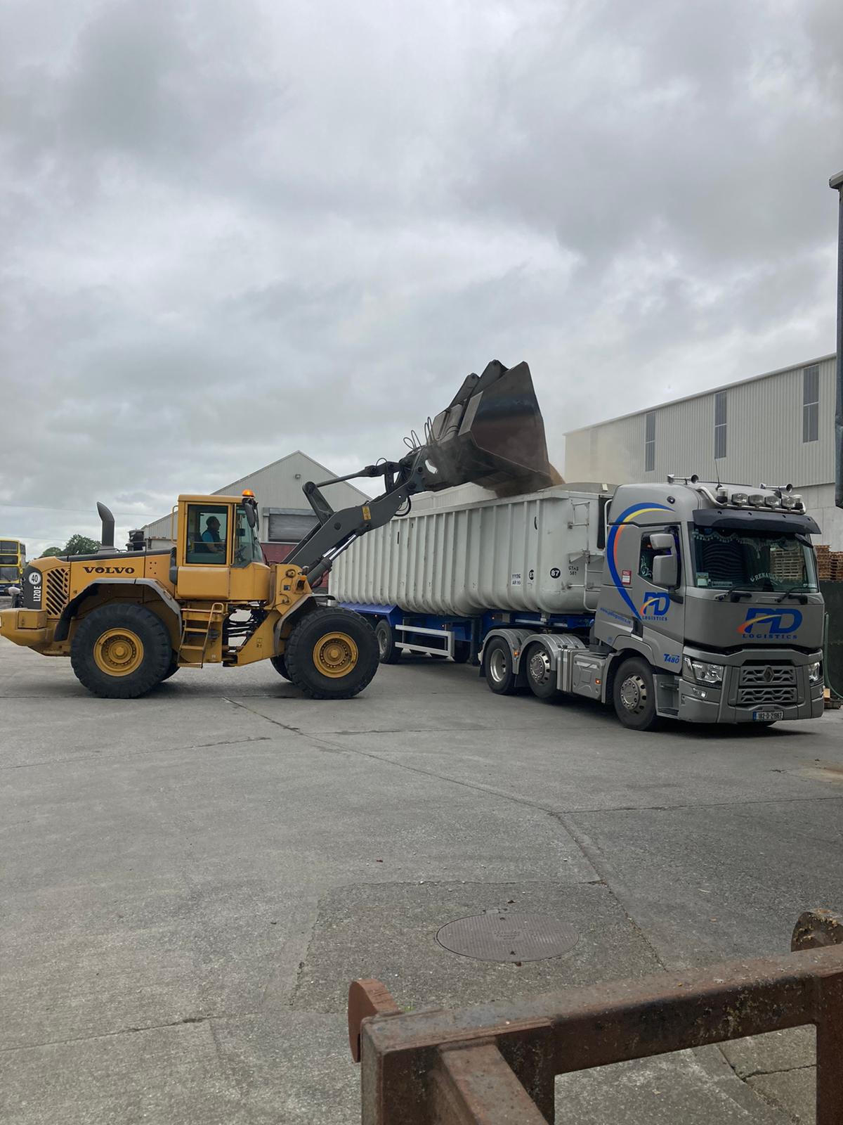 Loading shovel filling a PD Logistics trailer with excavated material